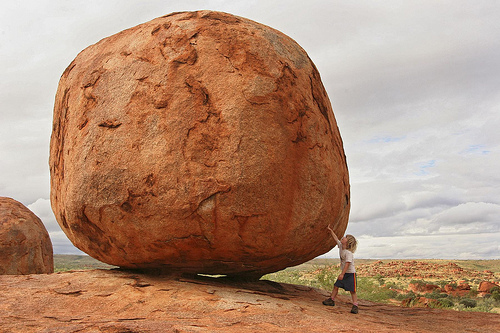 little boy looks at a big boulder, Devil's Marbles, Australia